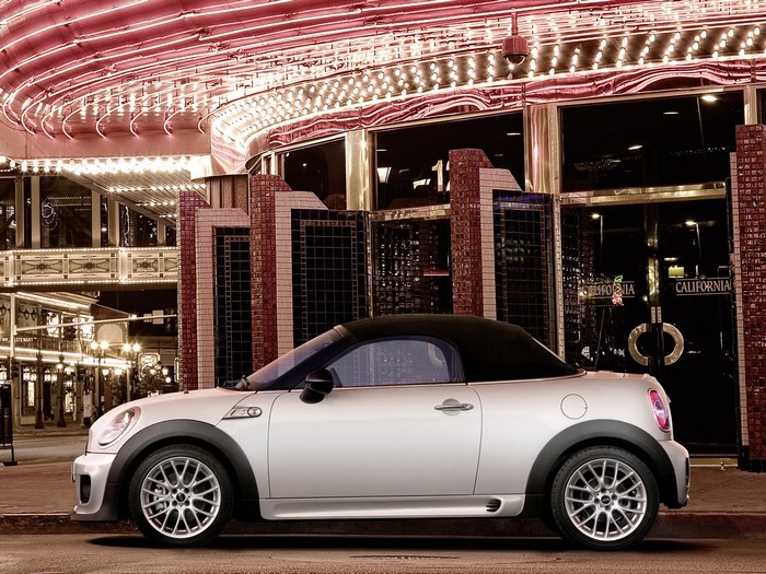 Mini Roadster parked in front of a neon-lit building