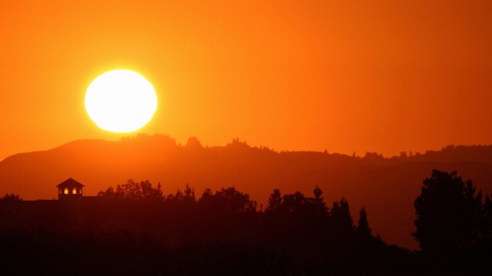 Sunset over rolling hills with a small gazebo