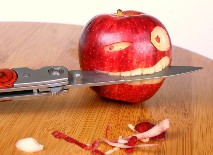 Apple carved into a face with a knife