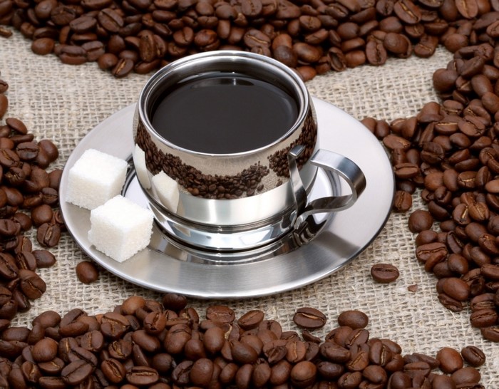 Cup of coffee with sugar cubes and coffee beans