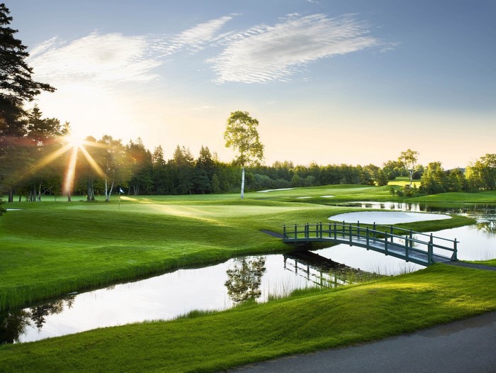 Golf course with bridge over water at sunrise