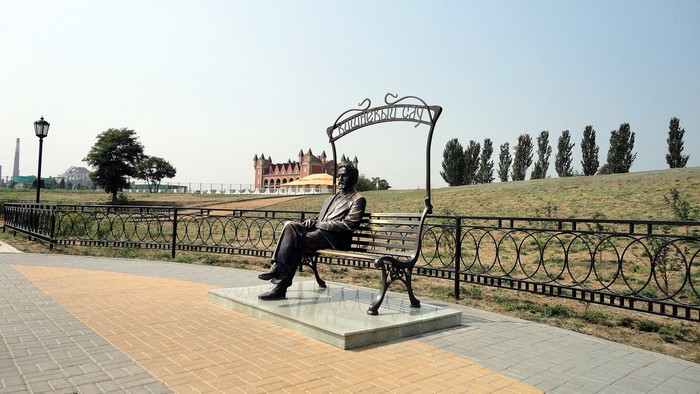 Statue of a man sitting on a bench in a park