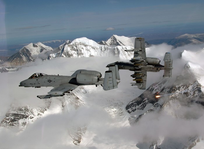 Two A-10 Thunderbolt II aircraft flying over snowy mountains
