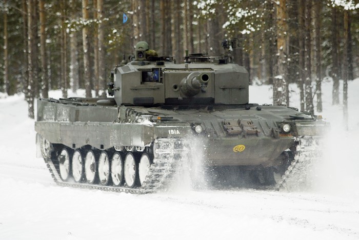 A tank drives through a snowy forest