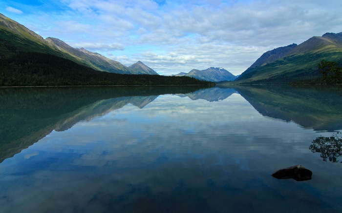 Mountains reflected in a calm lake under a cloudy sky