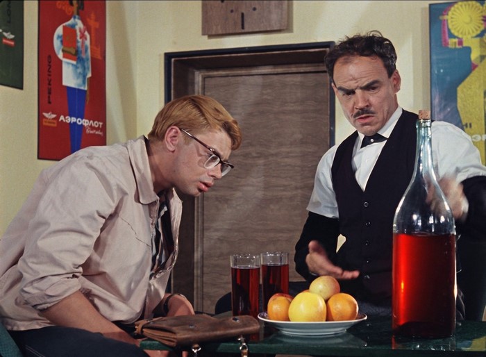 Two men at a table with drinks and fruit