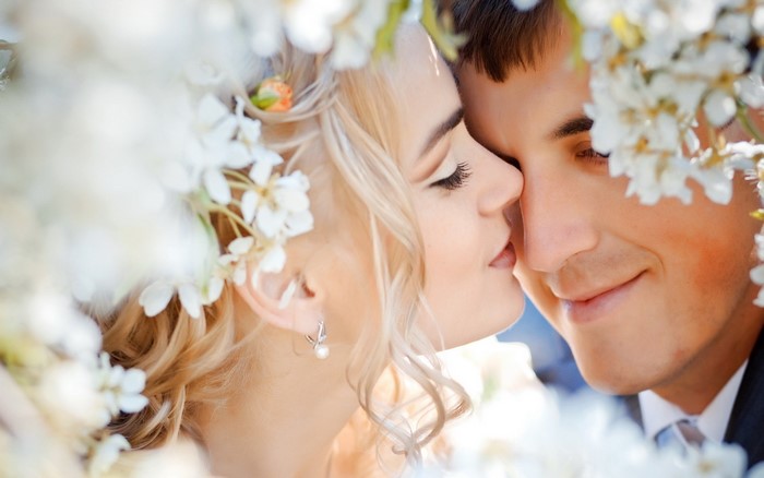 Bride and groom kissing among white flowers