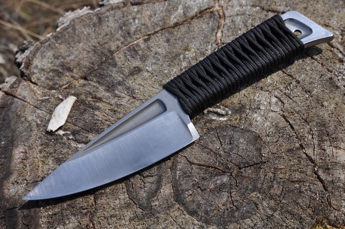 Knife with black paracord wrapped handle on a tree stump
