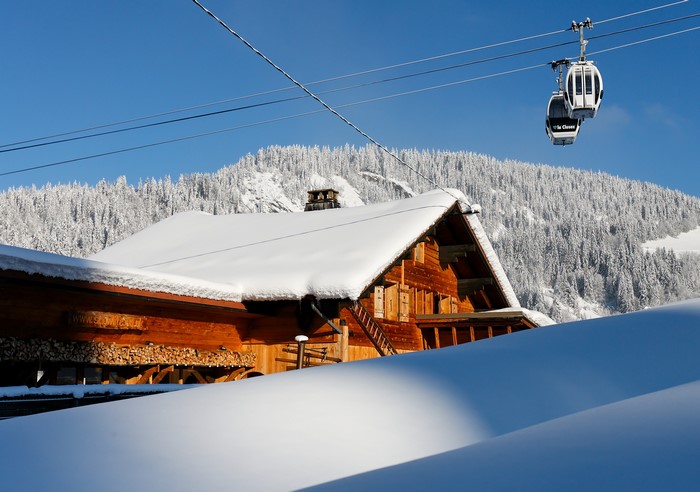Wooden chalet with snow-covered roof and ski lift