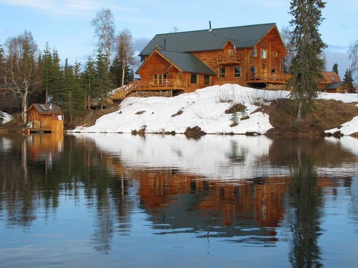 Log cabin on a snowy hill overlooking a lake in the USA