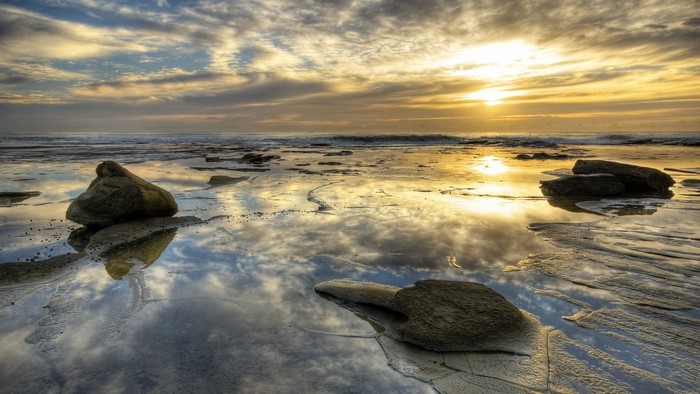 Sunset over the ocean with reflections on the beach
