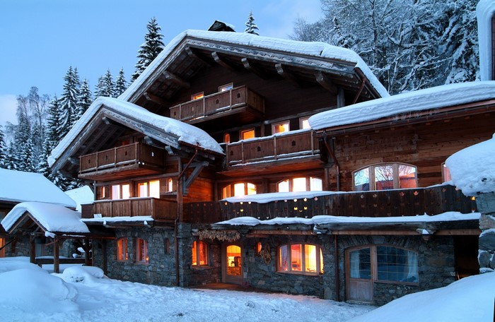 Wooden chalet with stone base in snowy mountains