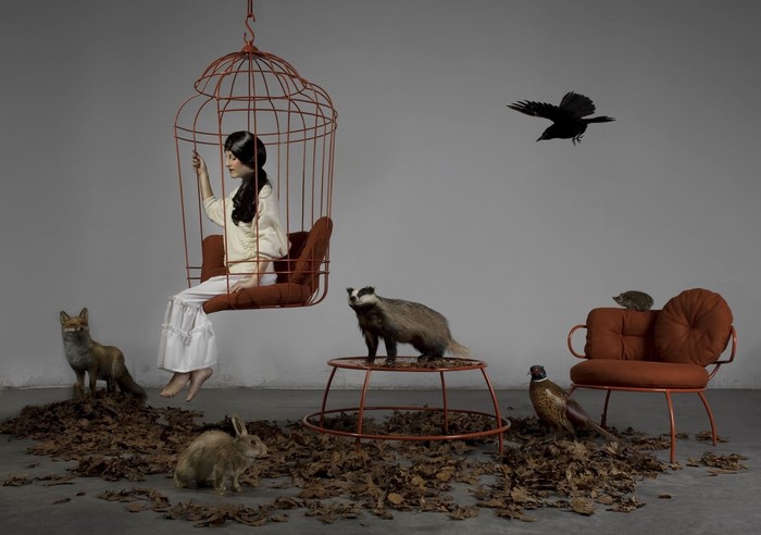 Girl in birdcage with taxidermied animals
