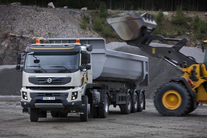 Volvo FMX dump truck being loaded by a wheel loader