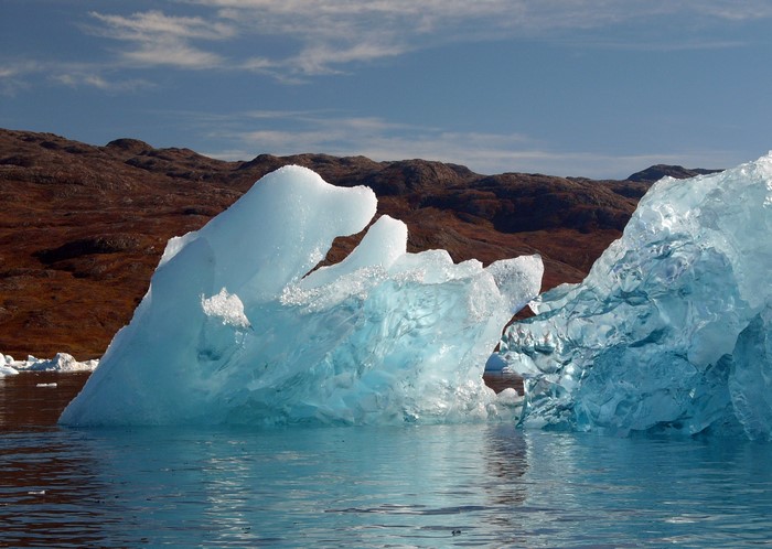 Icebergs floating in water with mountains in the background