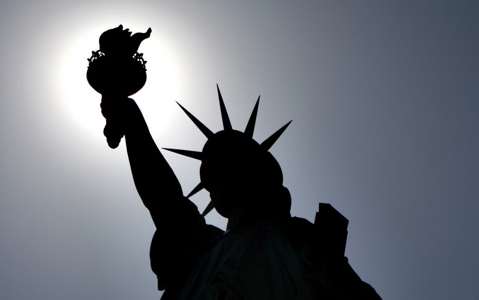 Statue of Liberty silhouette against the sun
