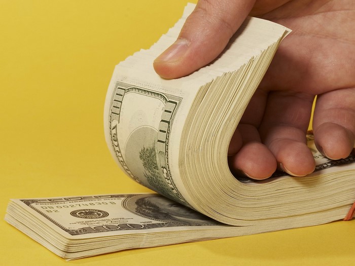 Hand holding a stack of US dollar bills
