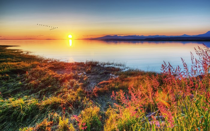 Sunrise over a calm lake with mountains in the distance