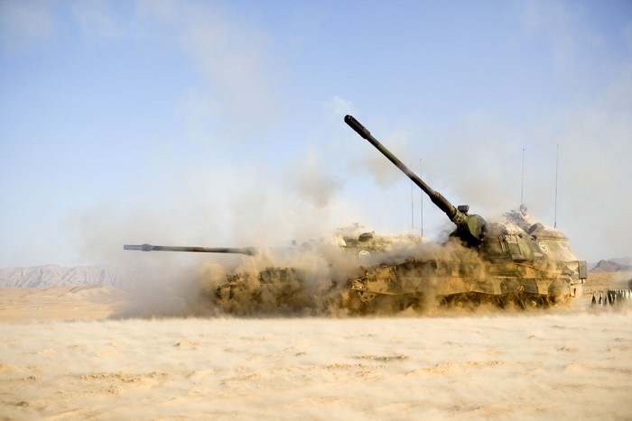 Two self-propelled howitzers firing in a desert