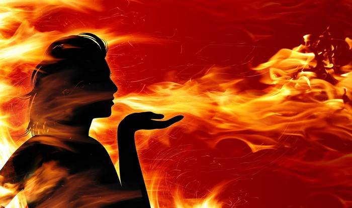 Silhouette of a woman blowing fire