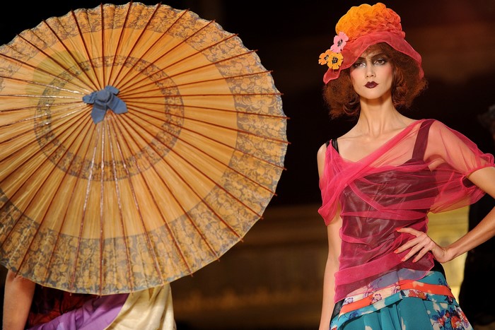 Model wearing a hat and dress with an umbrella