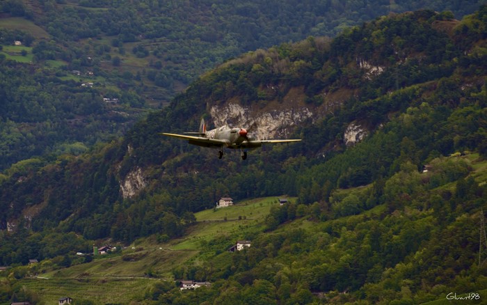 Airplane flying over a green mountainous landscape