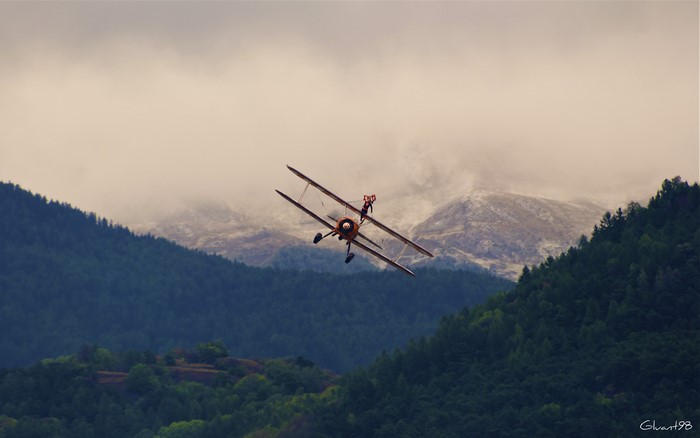 Biplane with wing walker over mountains