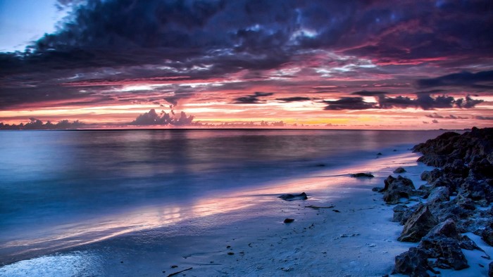 Sunset over a rocky beach with calm ocean