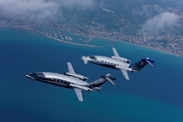 Two Piaggio P.180 Avanti aircraft flying over a coastline