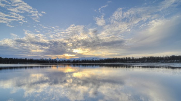 Sunrise over a calm lake with reflections