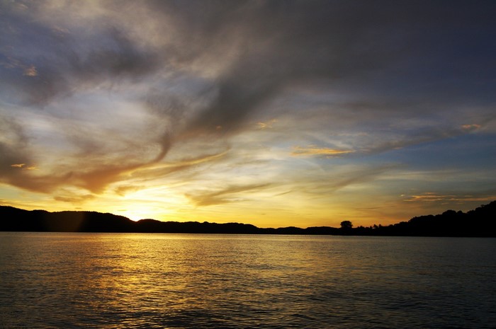 Sunset over a calm body of water with silhouetted hills