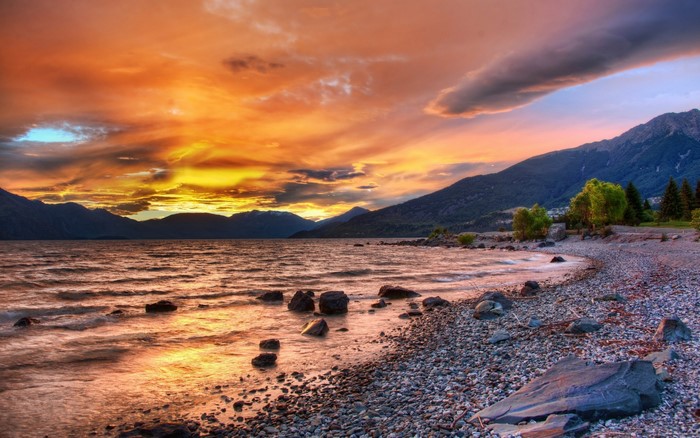Sunset over a rocky lake shore with mountains