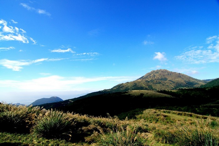 Grassy mountains under a blue sky with clouds