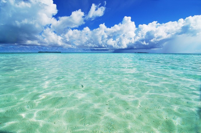 Turquoise ocean water with clouds and distant islands