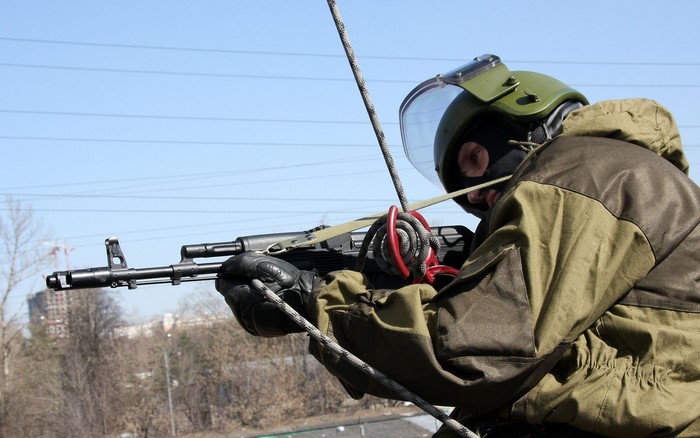 Soldier in tactical gear rappelling with rifle