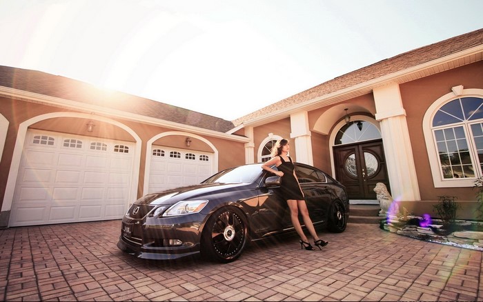 Woman in black dress with Lexus in front of house