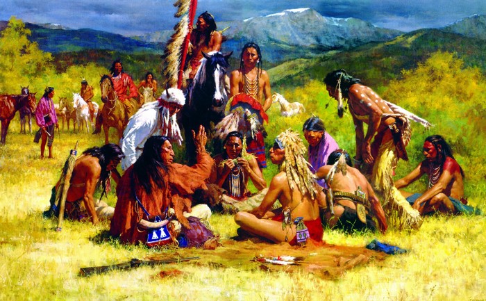 Native American men gathered in a field with mountains in the background