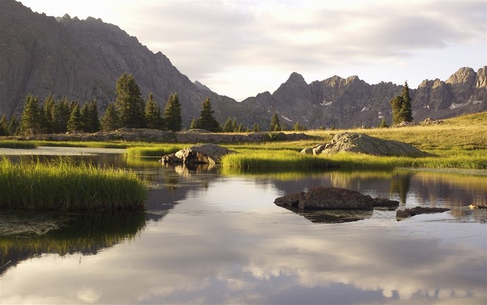Mountains reflected in a calm lake with grassy islands