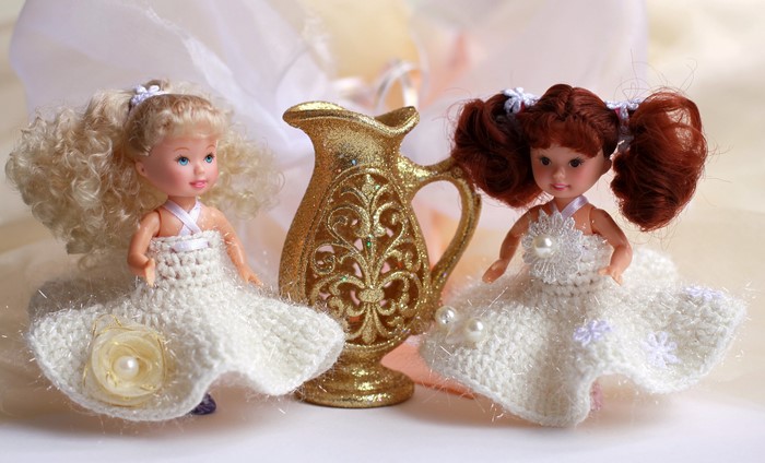 Two dolls in white dresses with a golden pitcher