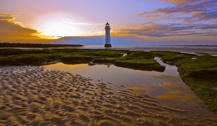 Lighthouse on a beach at sunset