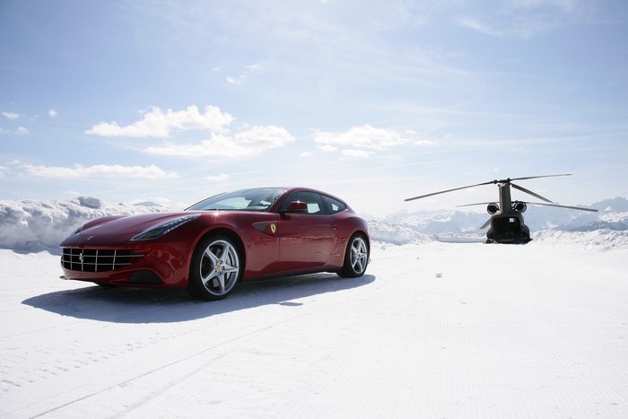 Red Ferrari and helicopter in snowy mountains