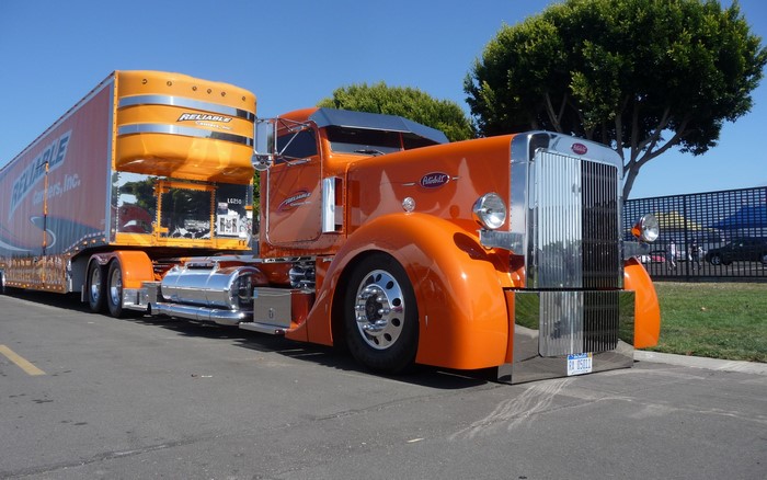 Orange Peterbilt semi-truck with Reliable Carriers trailer
