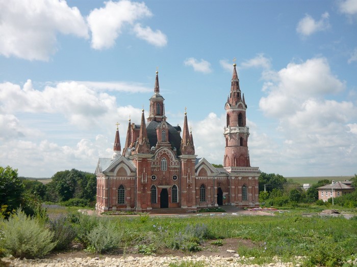 Red brick church with spires and bell tower