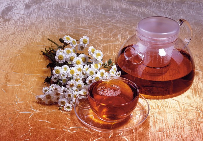 Tea in a glass teapot and cup with flowers