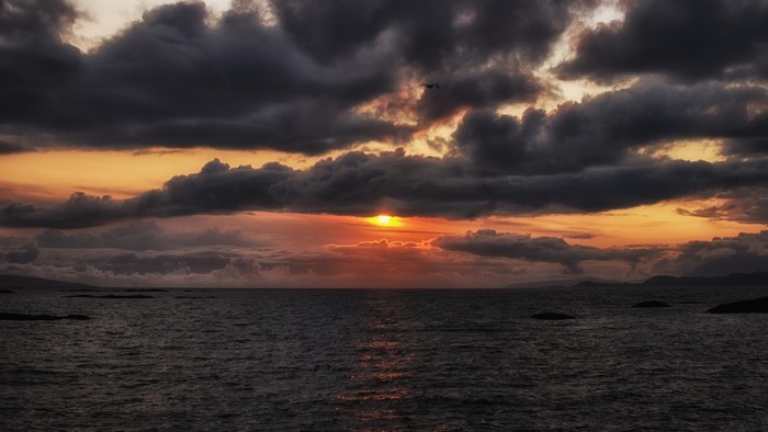 Sunset over the ocean with dark clouds