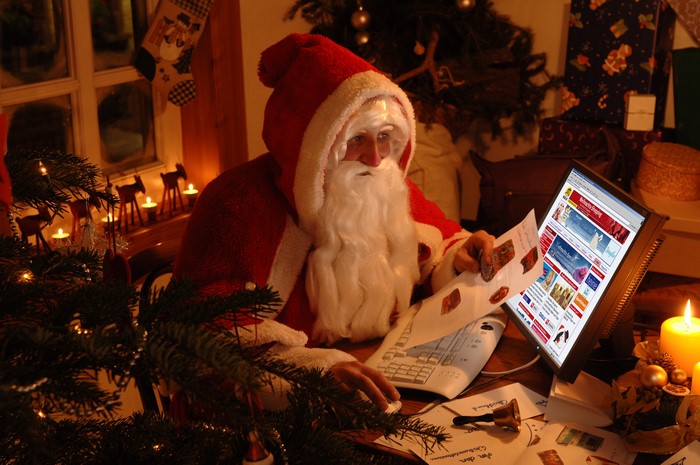 Santa Claus using a computer on Christmas