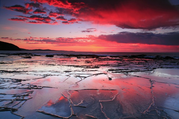 Sunset over rocky coastline with colorful clouds