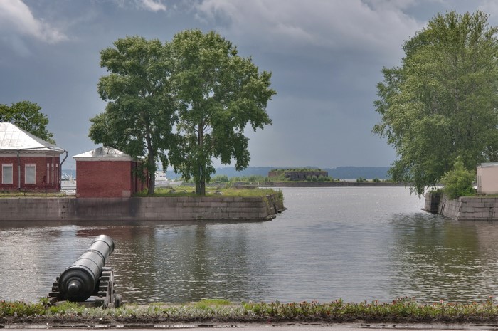 Cannon in front of buildings and water in Russia