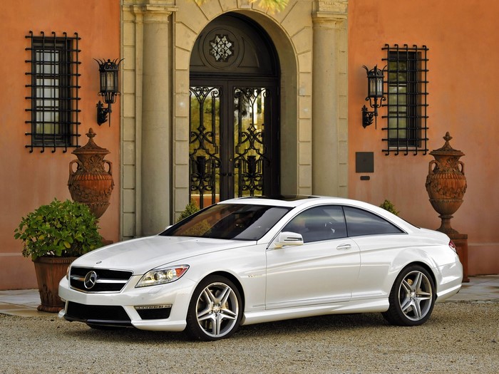 White Mercedes-Benz CLS 63 AMG Coupe in front of a mansion