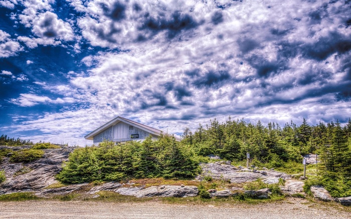 White building on a rocky hill with trees